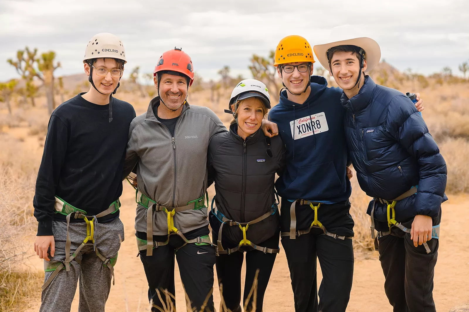 Group of five smiling for camera, all in climbing harnesses.