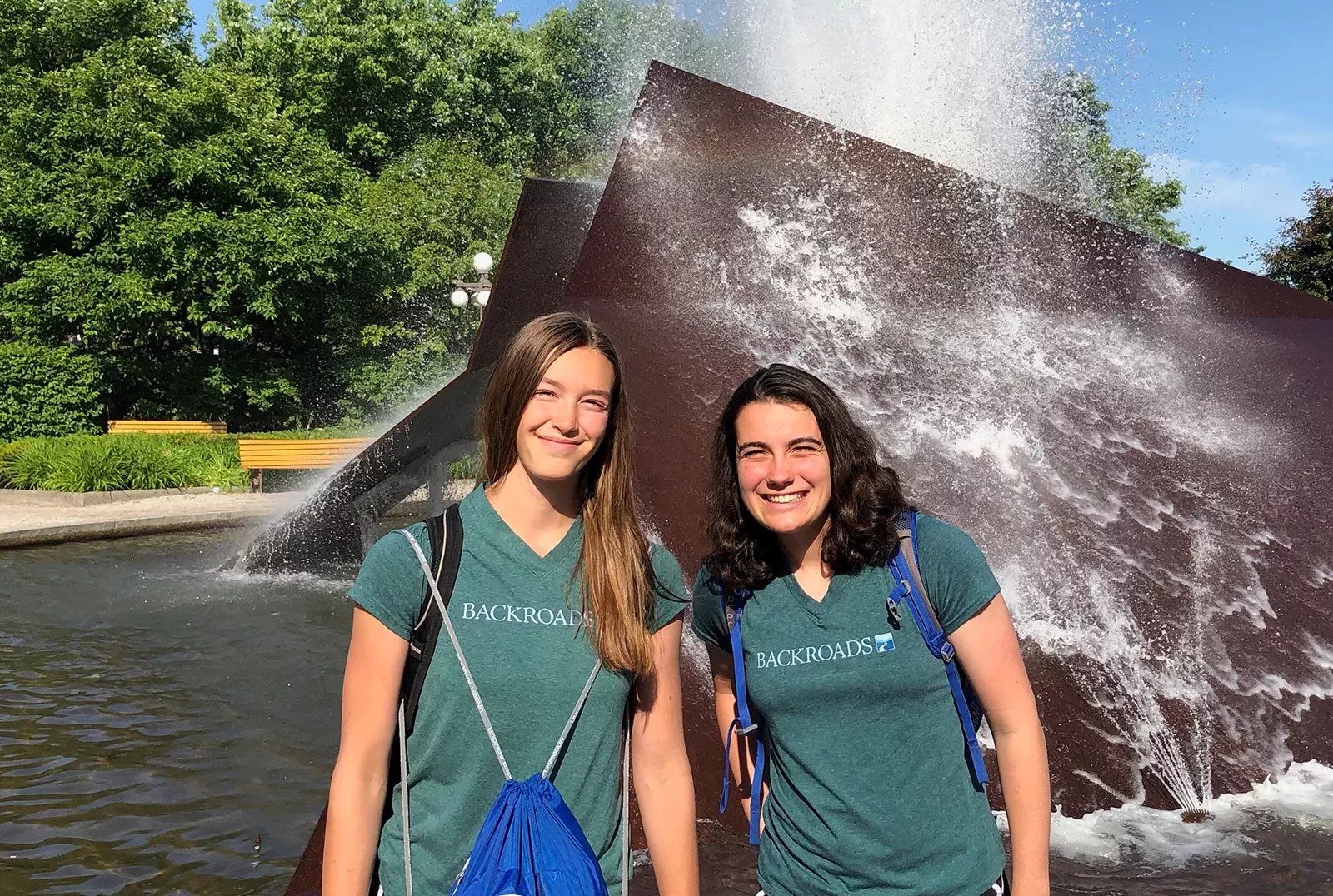 Two young guests smiling in front of a water sculpture.
