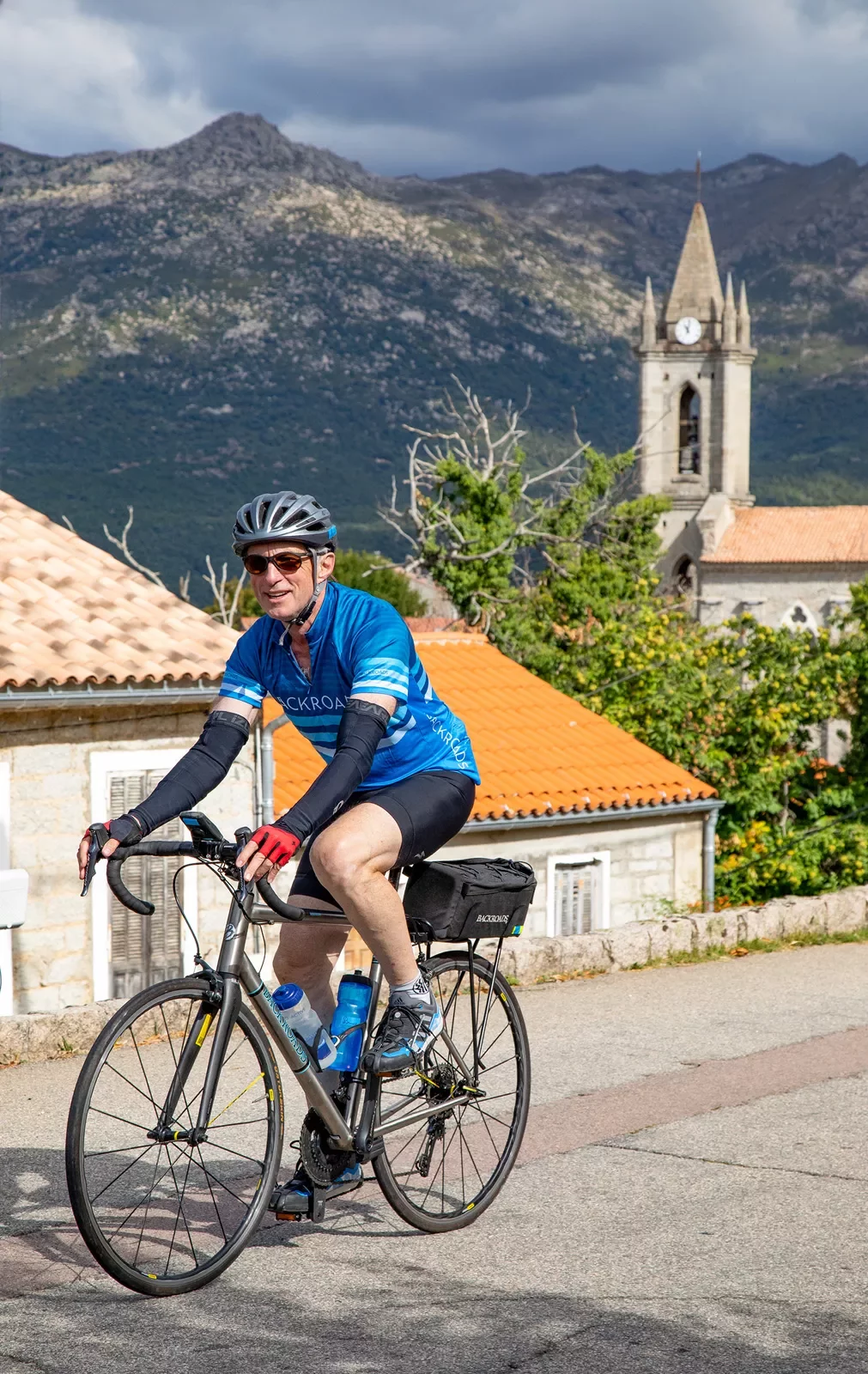 Guest cycling in Italian village, clock tower in background.