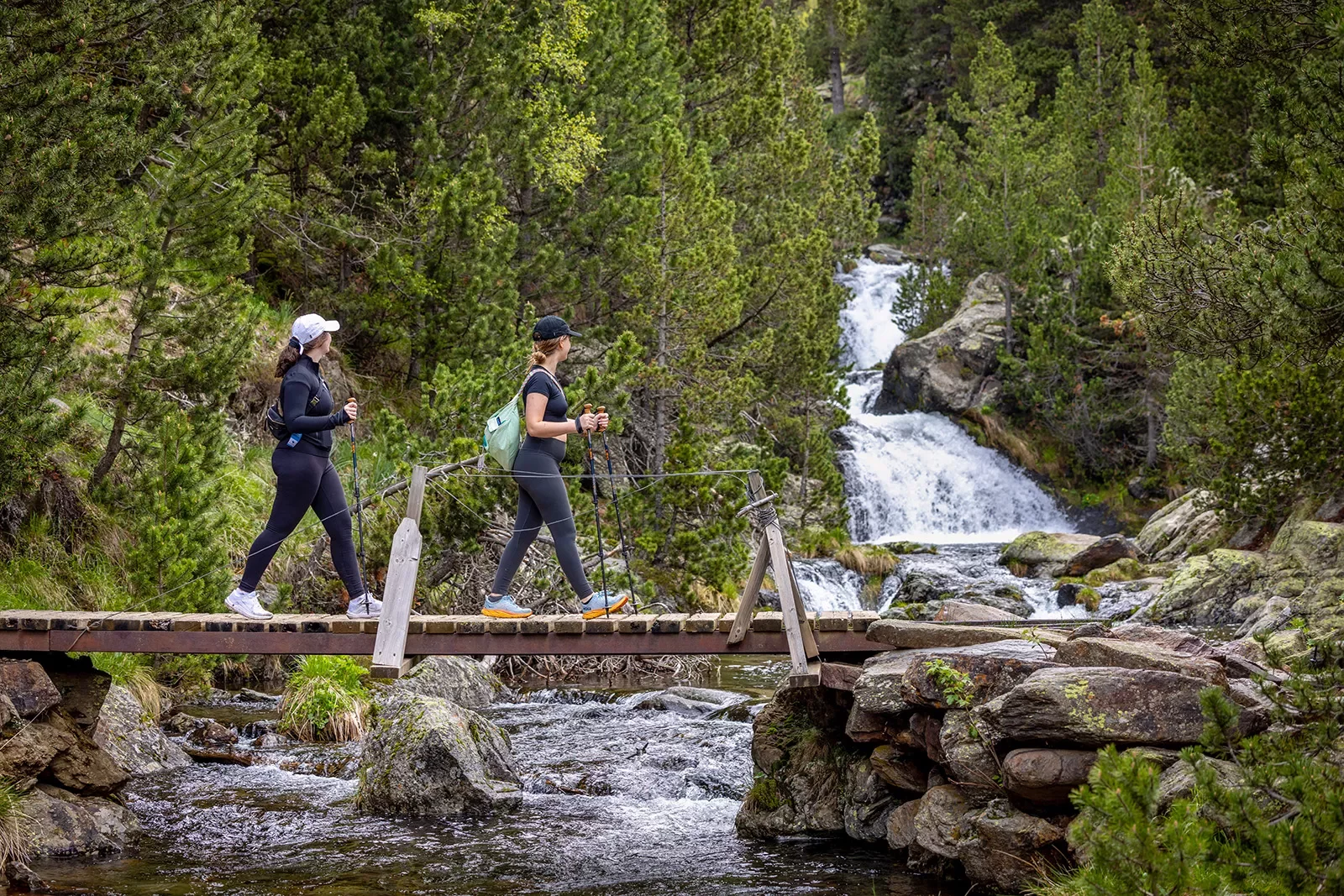 Hiking across a bridge with a waterfall in the background