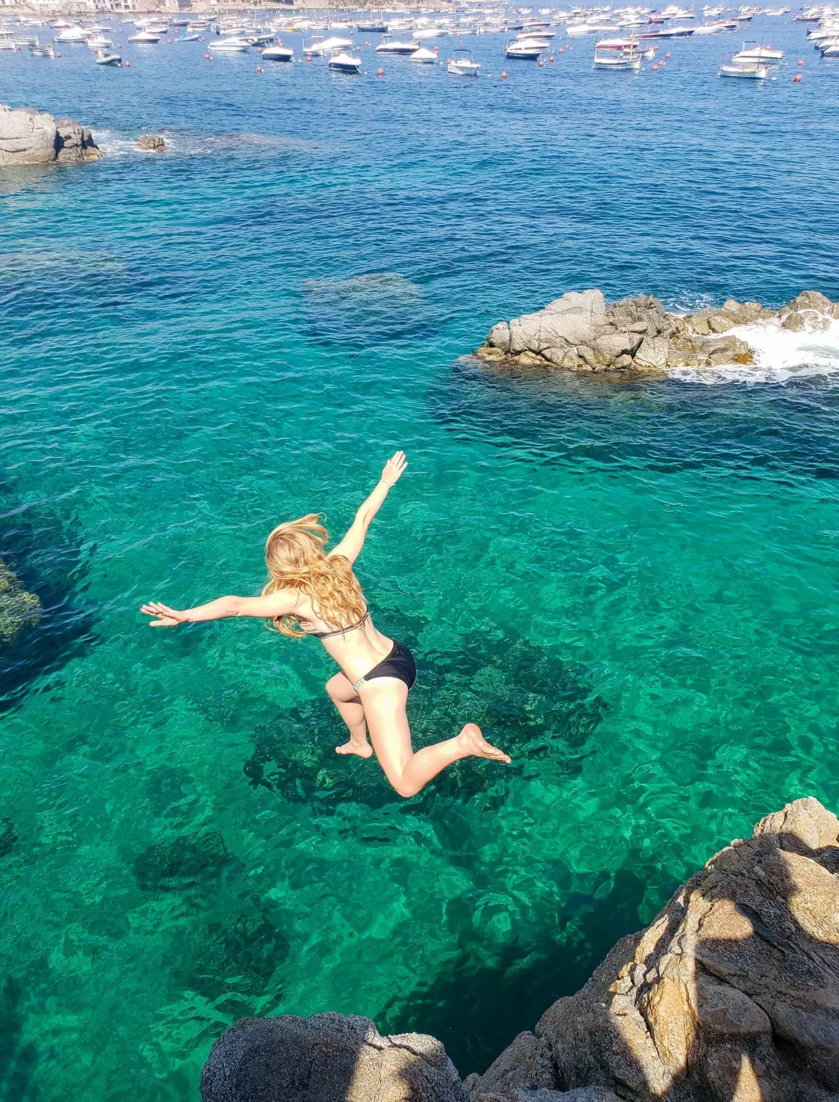 Teenage girl jumping into clear blue-green waters