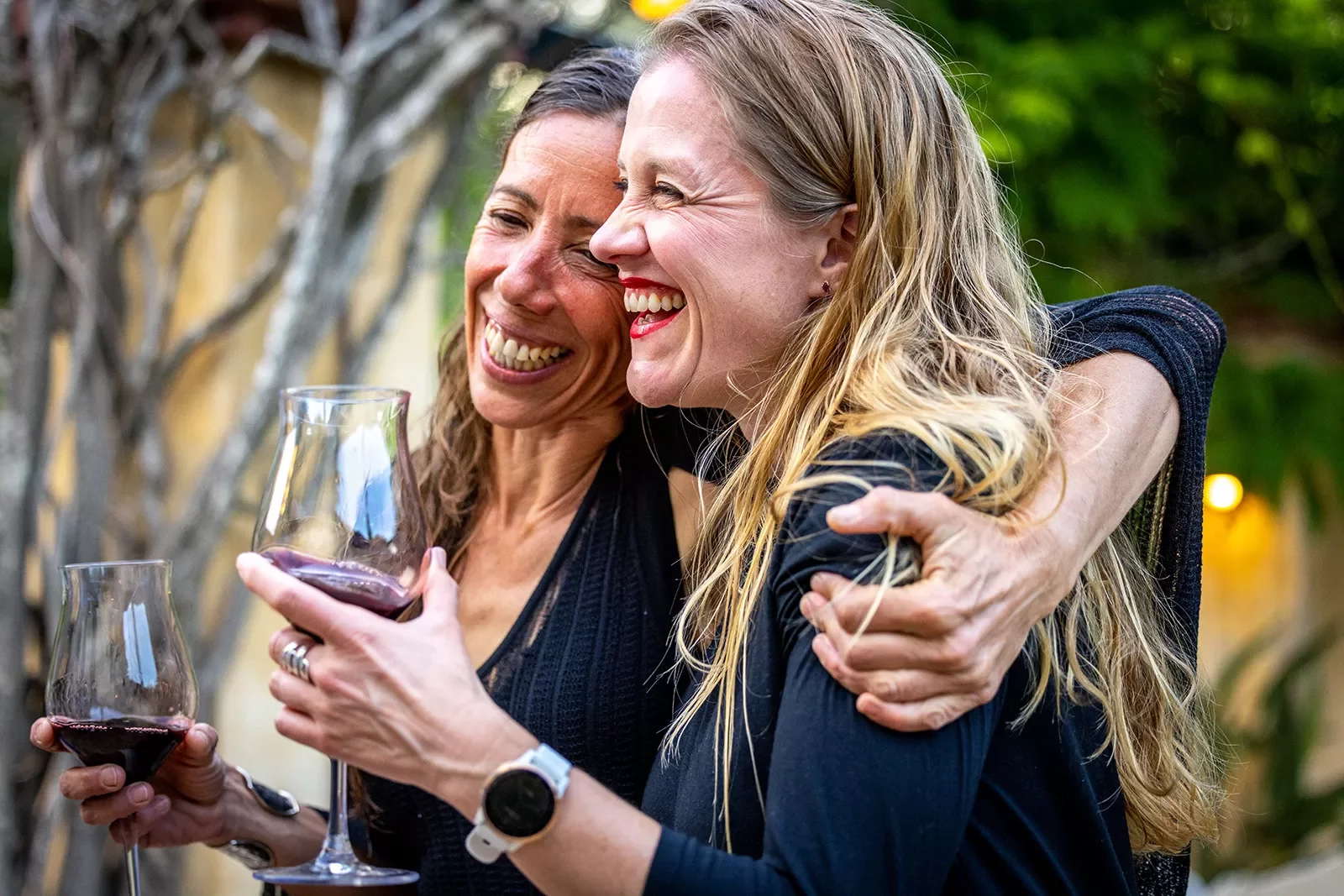 Two women holding glasses of wine and hugging