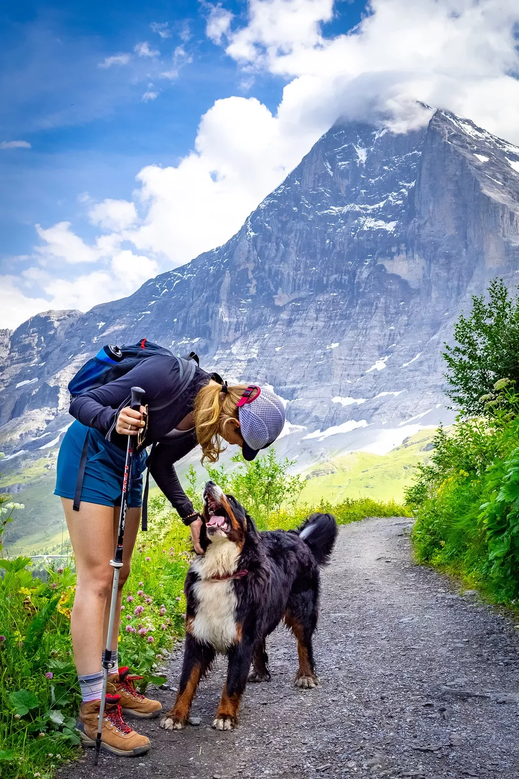 Guest with dog on trail, large cloud covered mountain in background.