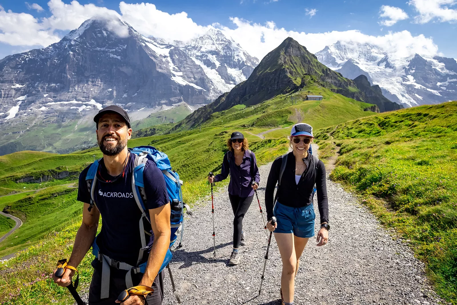 Three guests walking towards camera, Mount Eiger in background.