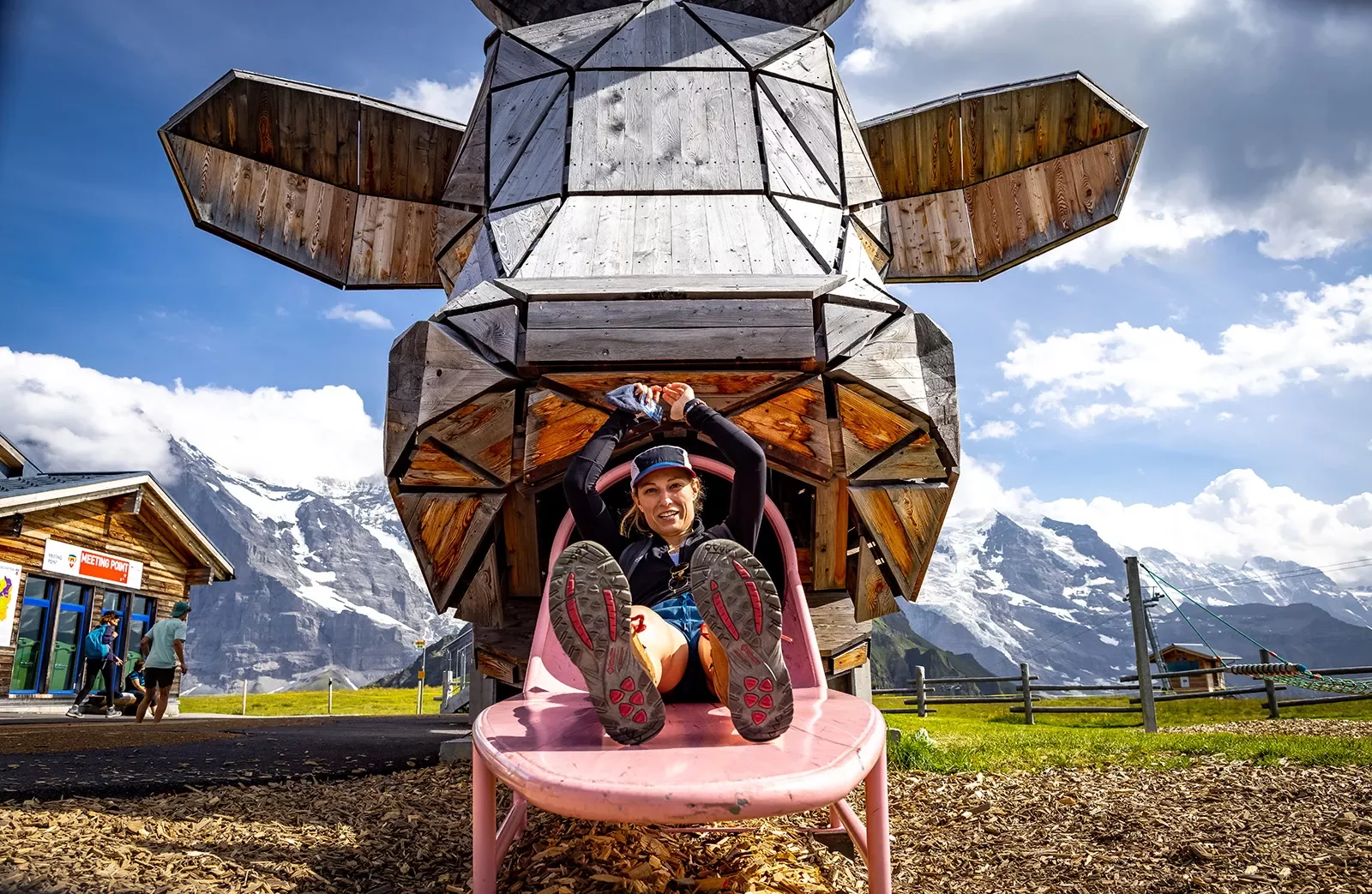Guest sitting on bench below large wooden cow-head sculpture.