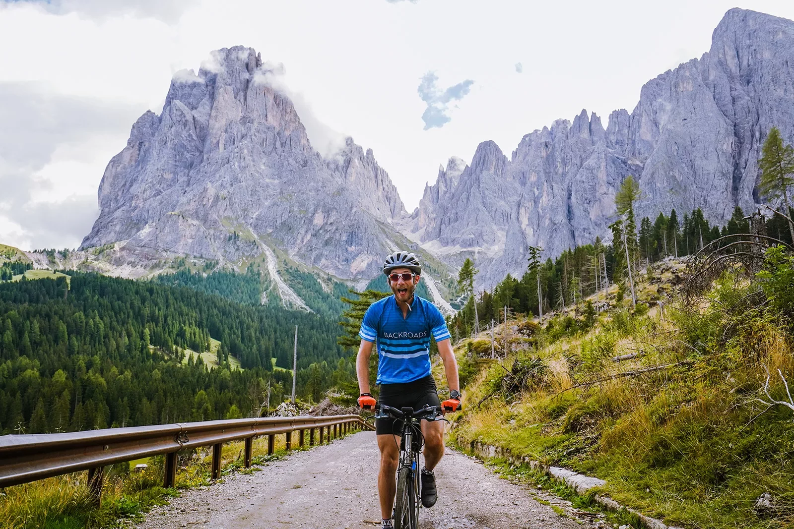 Guest cycling directly towards camera, large, craggy mountains in background.