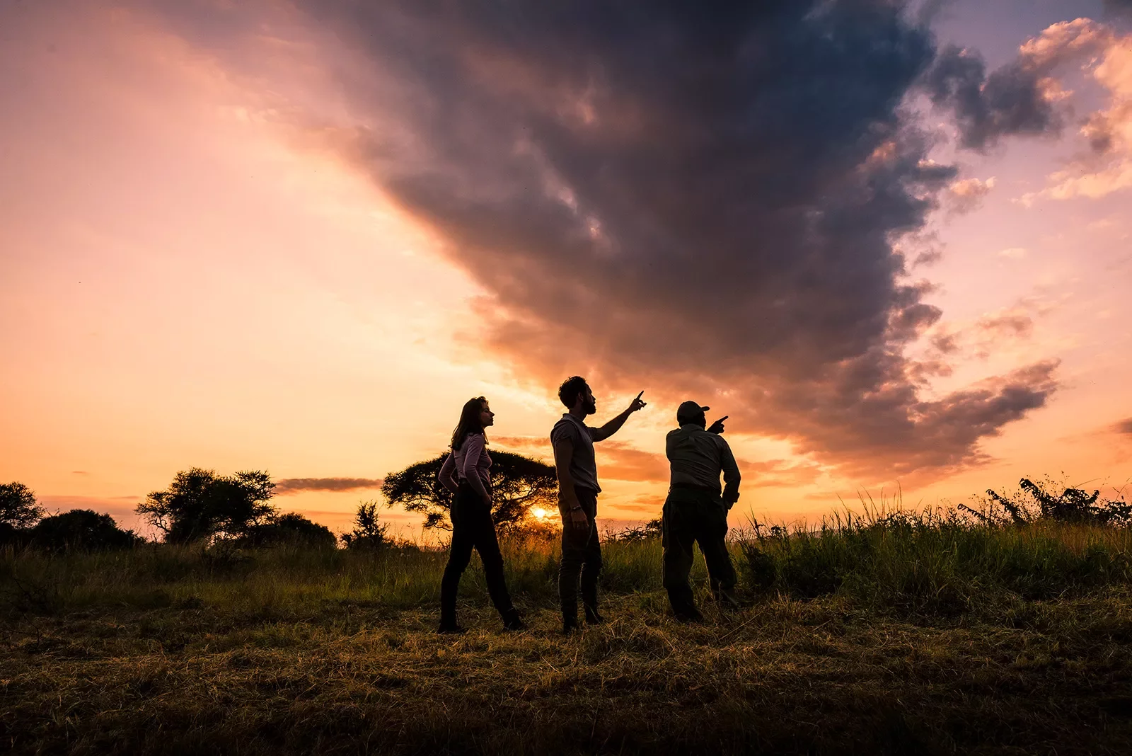 Three travelers looking off camera with African sunset in the background