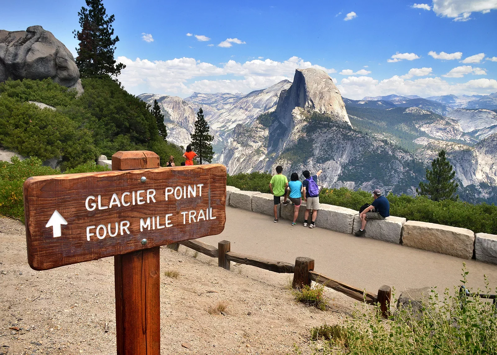 &quot;GLACIER POINT&quot; sign in foreground, guests and mountain in background.