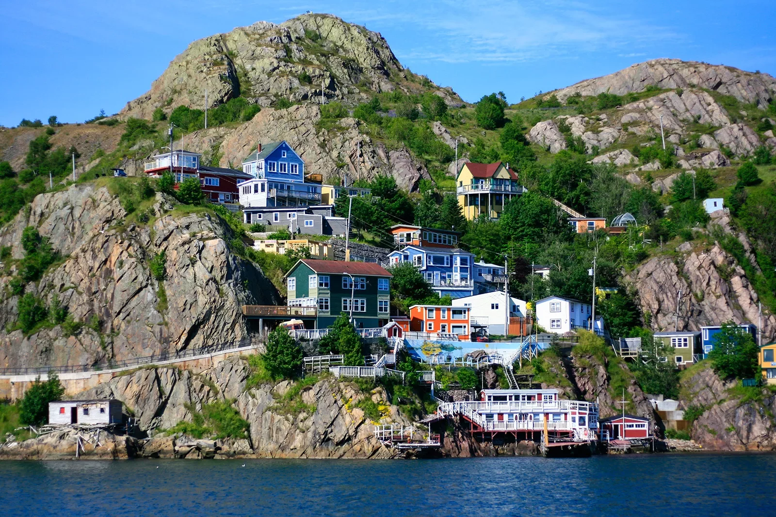 Wide shot of colorful coastal town in hillside. water below.