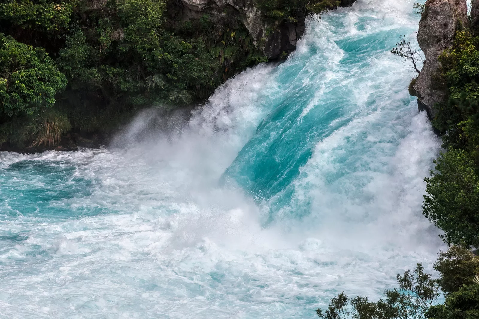 Wide shot of vibrant blue rushing waterfall.