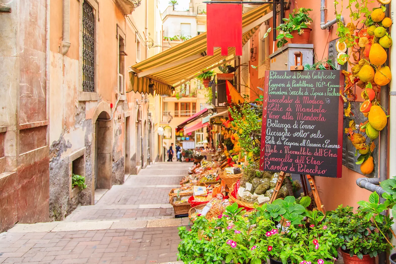 Alleyway shot of Italian restaurant, menu, hanging fruit, baskets behind.