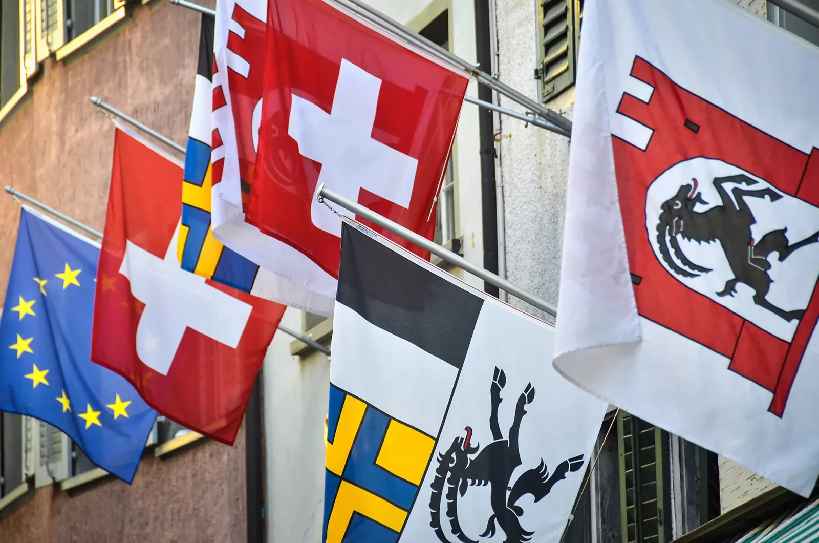 Swiss flags hanging on side of hotel.
