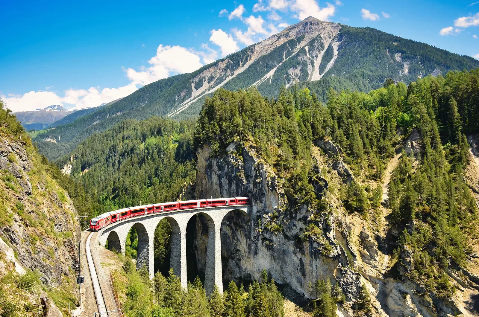 Landwasser viaduct in the Davos mountains near Filisur. Beautiful old stone bridge with a moving train.