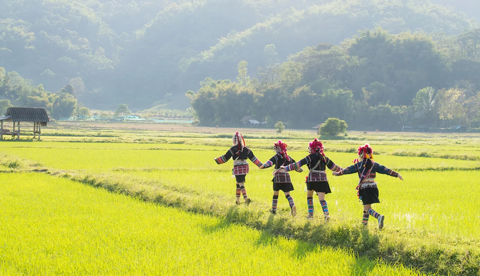 Thai people in traditional clothes running through a green field