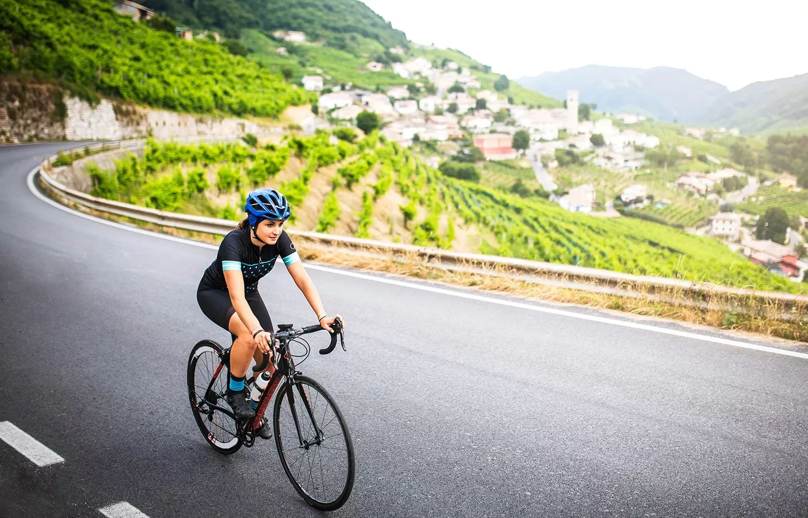 Guest cycling past vineyard, hillside town.