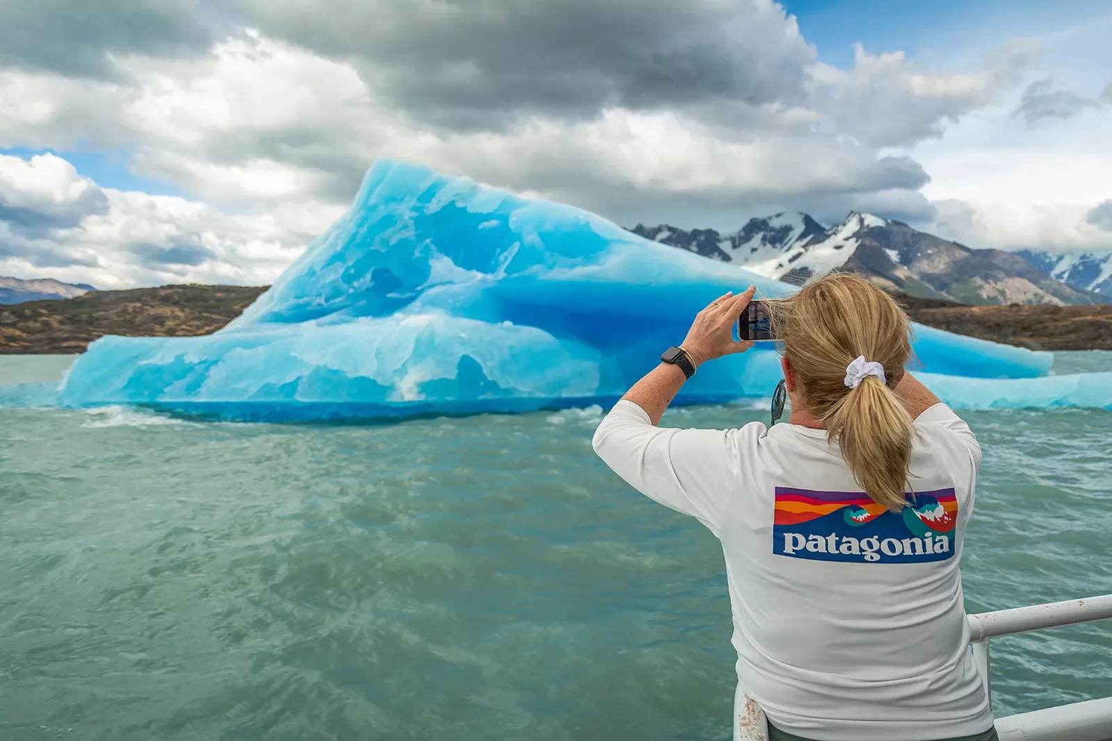 Woman on boat taking picture of a glacier in Patagonia.
