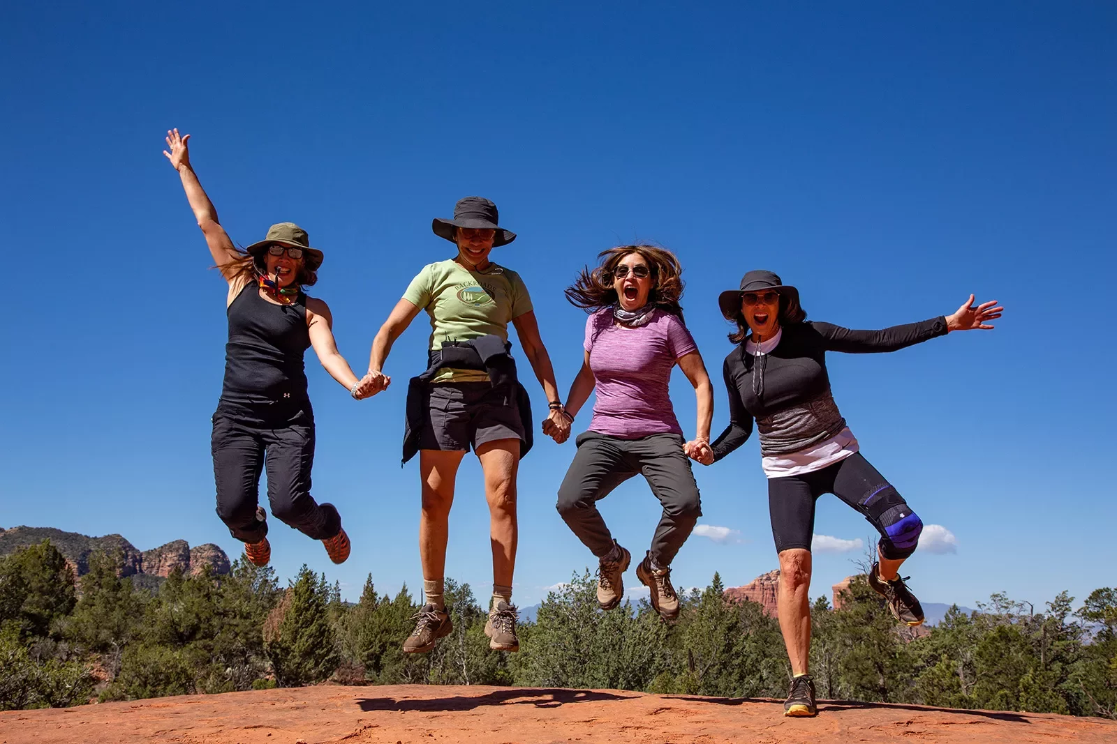 Four women jumping, posing for photo.