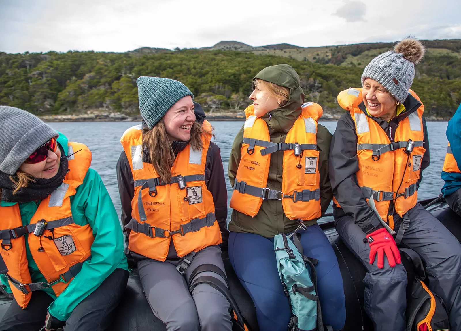 Four guests on raft in life-vests, all smiling.