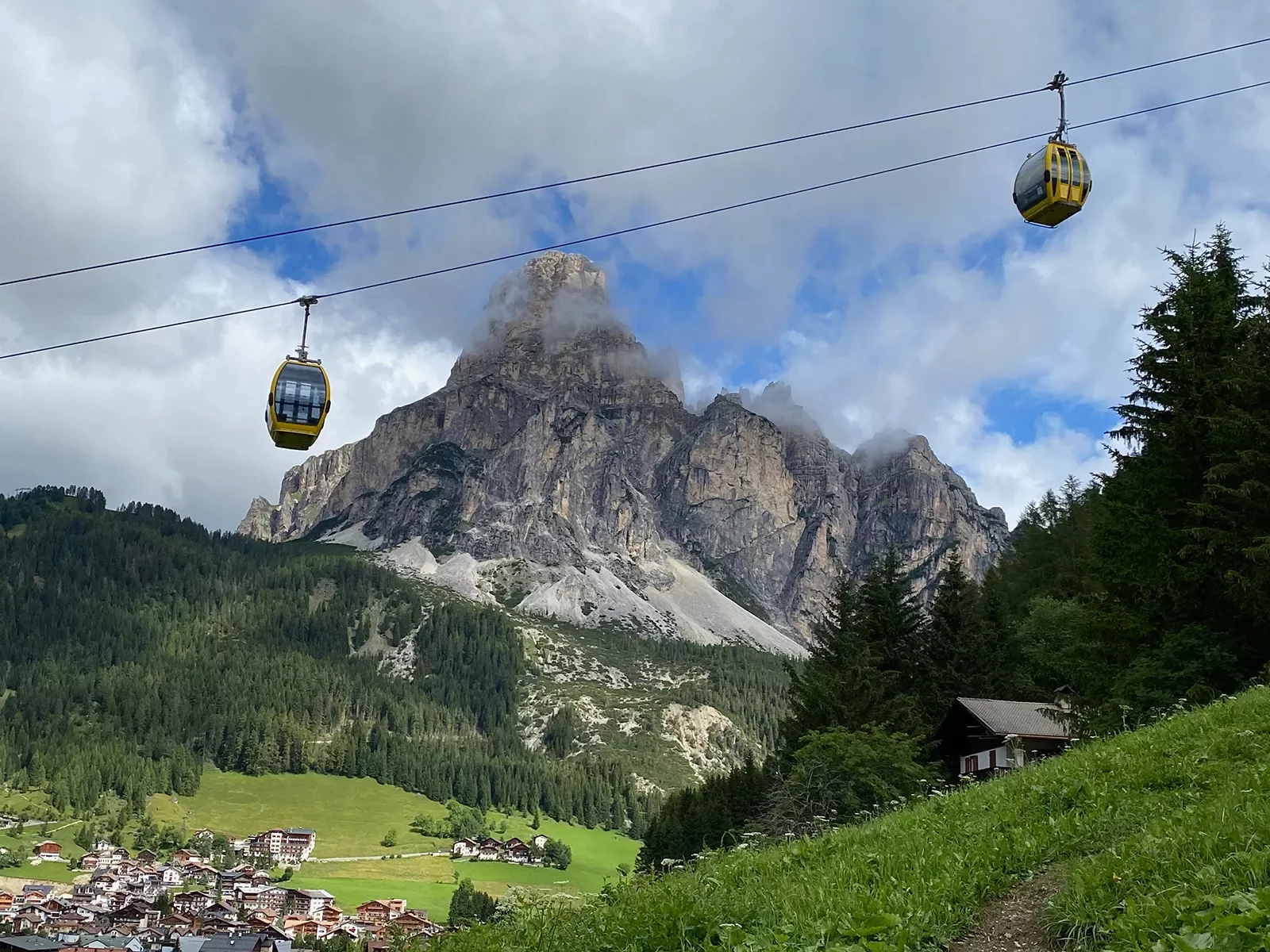 Shot of mountain village, gondola, mountain, village in distance.