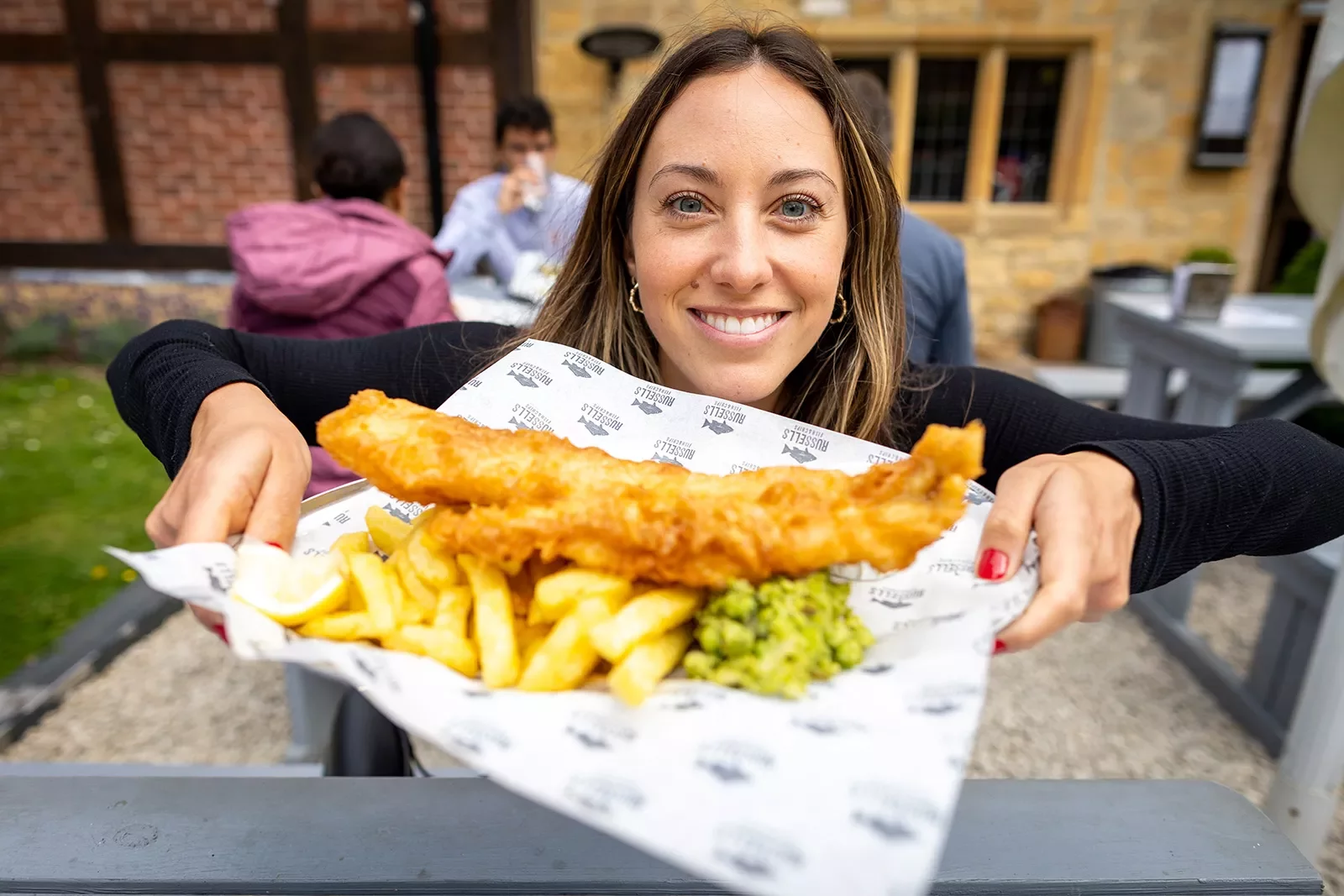 Backroads guest posing with fish and chips plate in England.
