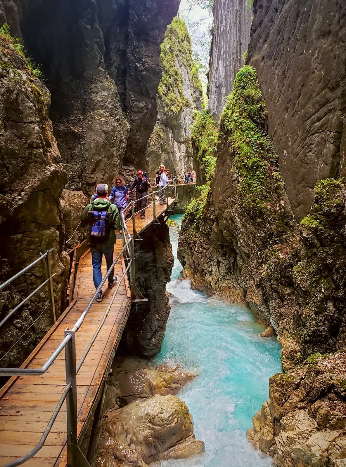 Hikers on bridge over waterfall in Bavaria.