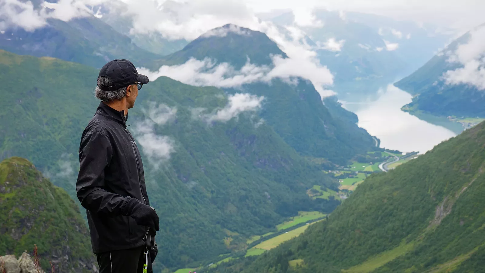 Solo hiker looking out over a lush green valley in Norway