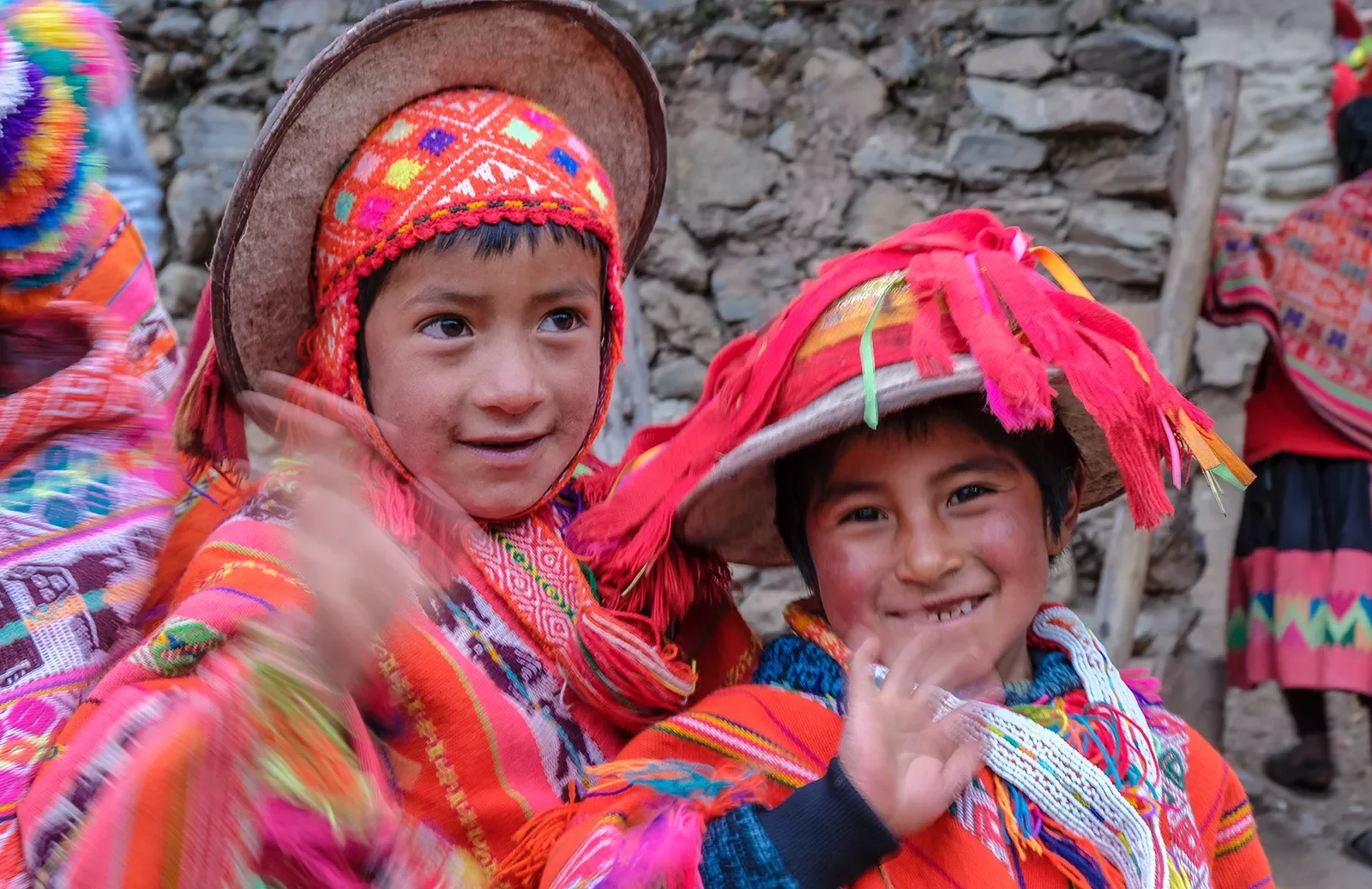 Two children in vibrant pink and red traditional Peruvian clothes.