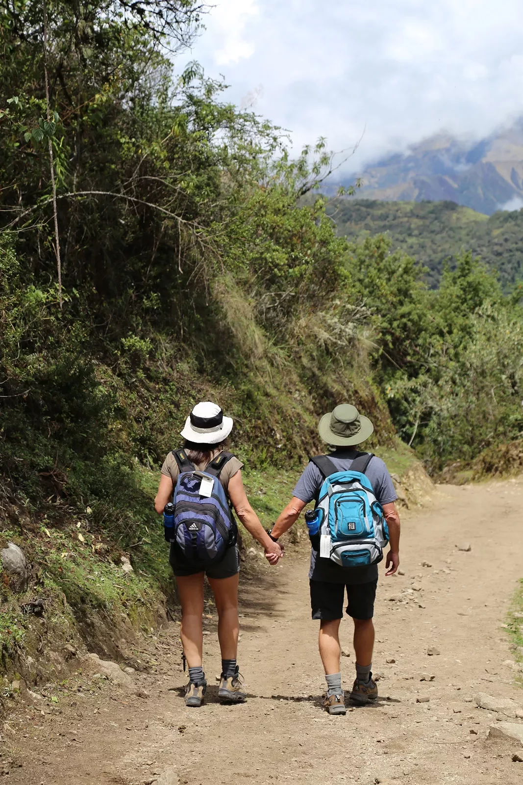 Two guests walking down mountain trail while holding hands.