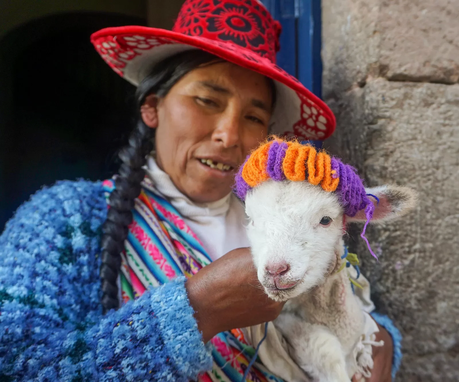 Local woman holding a small white goat, both facing camera.