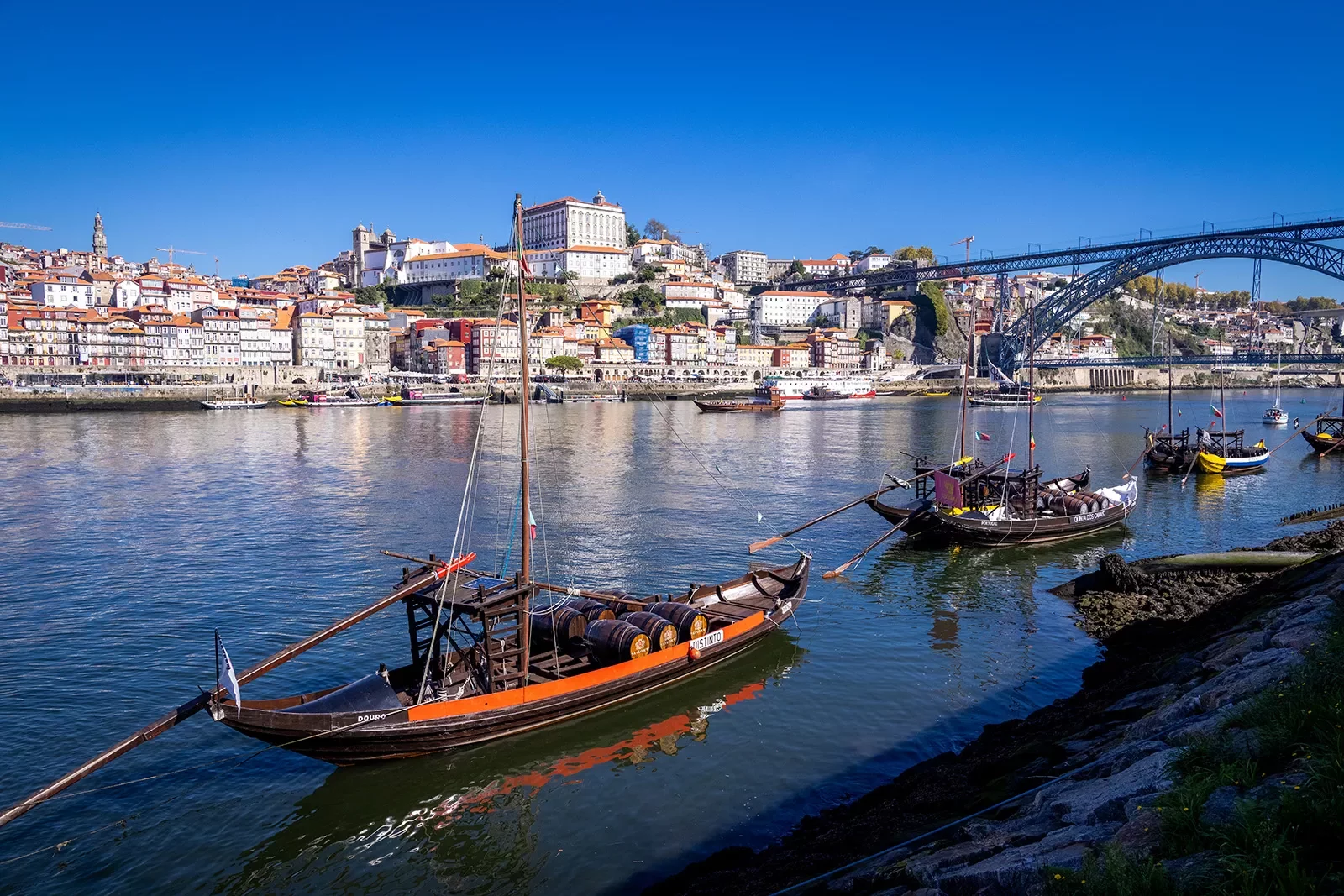 Shot of Porto river, boats, riverside houses, bridge in distance.