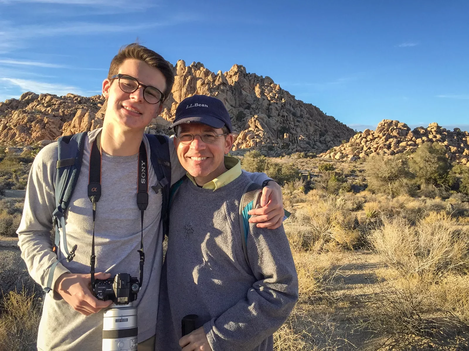 Two guests posing for desert photo, one has a camera.