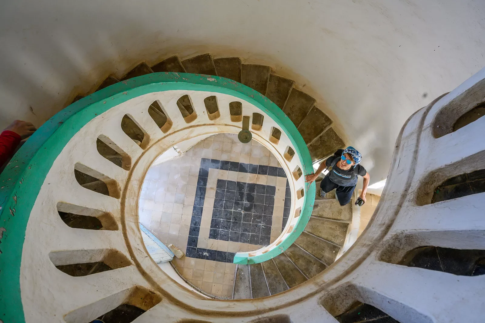 Looking down from a spiral staircase while a traveler looks up