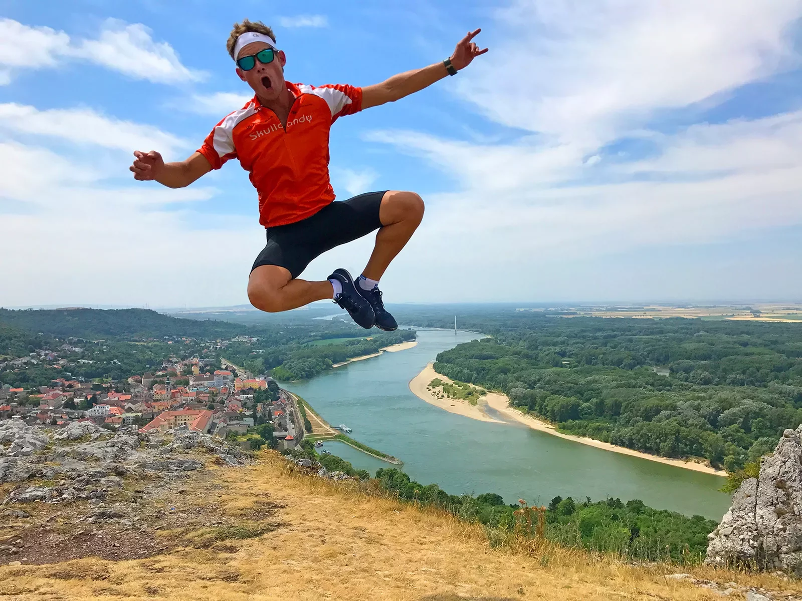 Man jumping up on a cliffside with a river in the distance