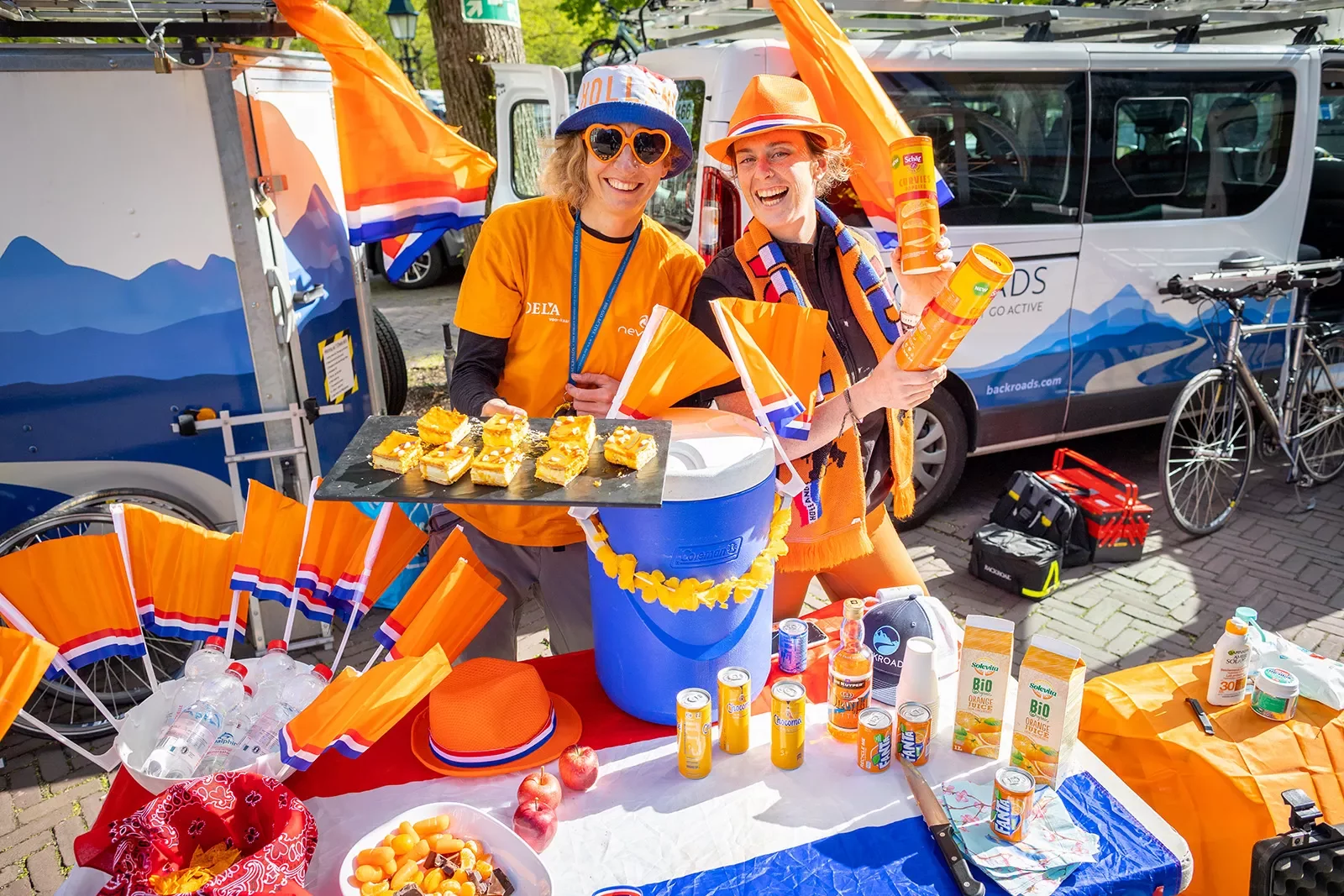 Man and women in orange clothing holding up pastries
