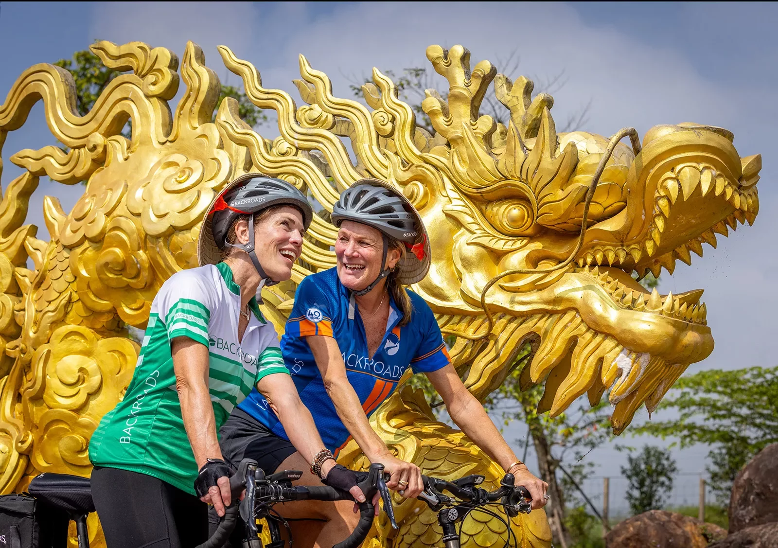 Women biking in front of a gold dragon statue