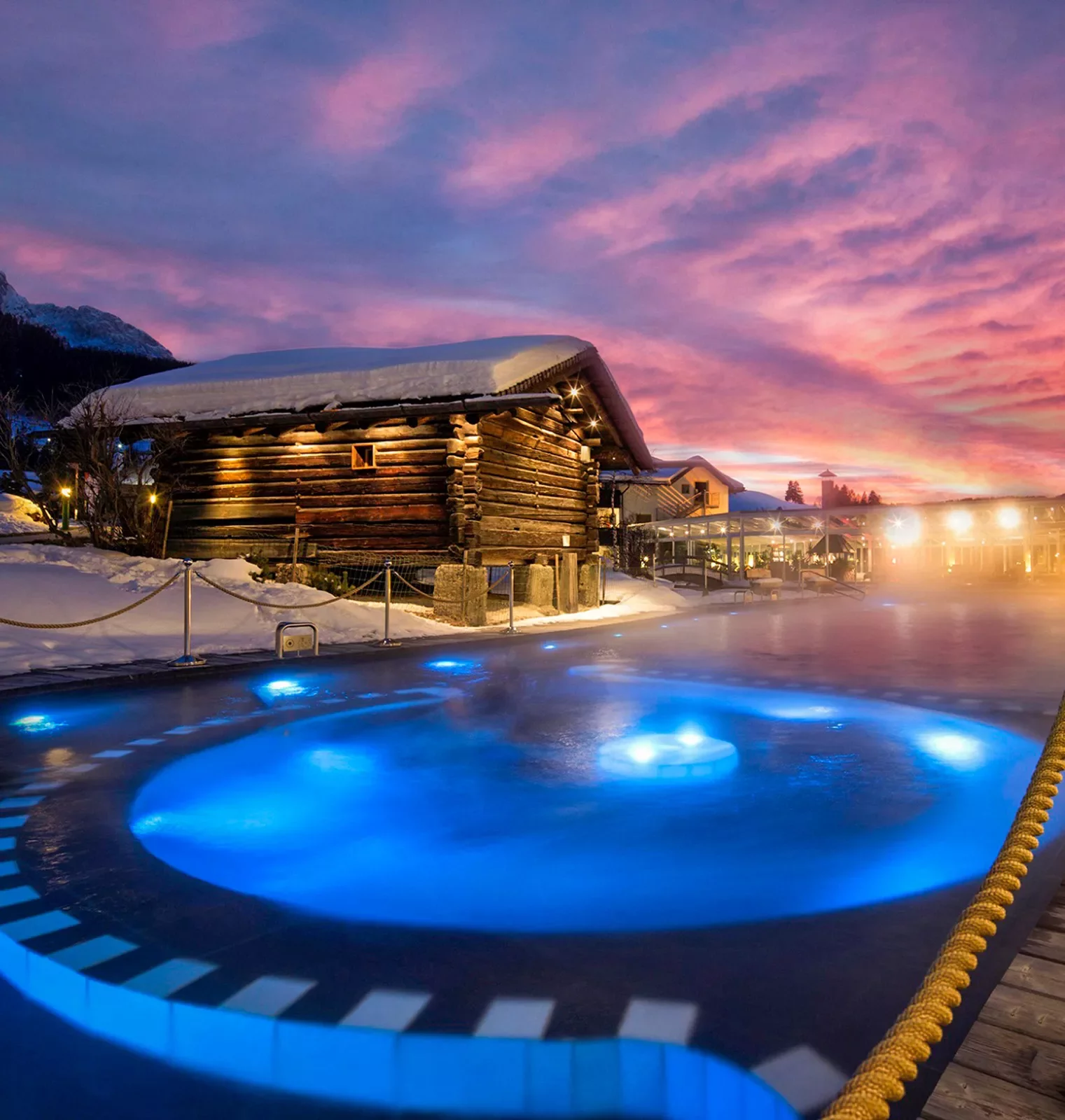 Northern lights shine over a small lodge and hot tub