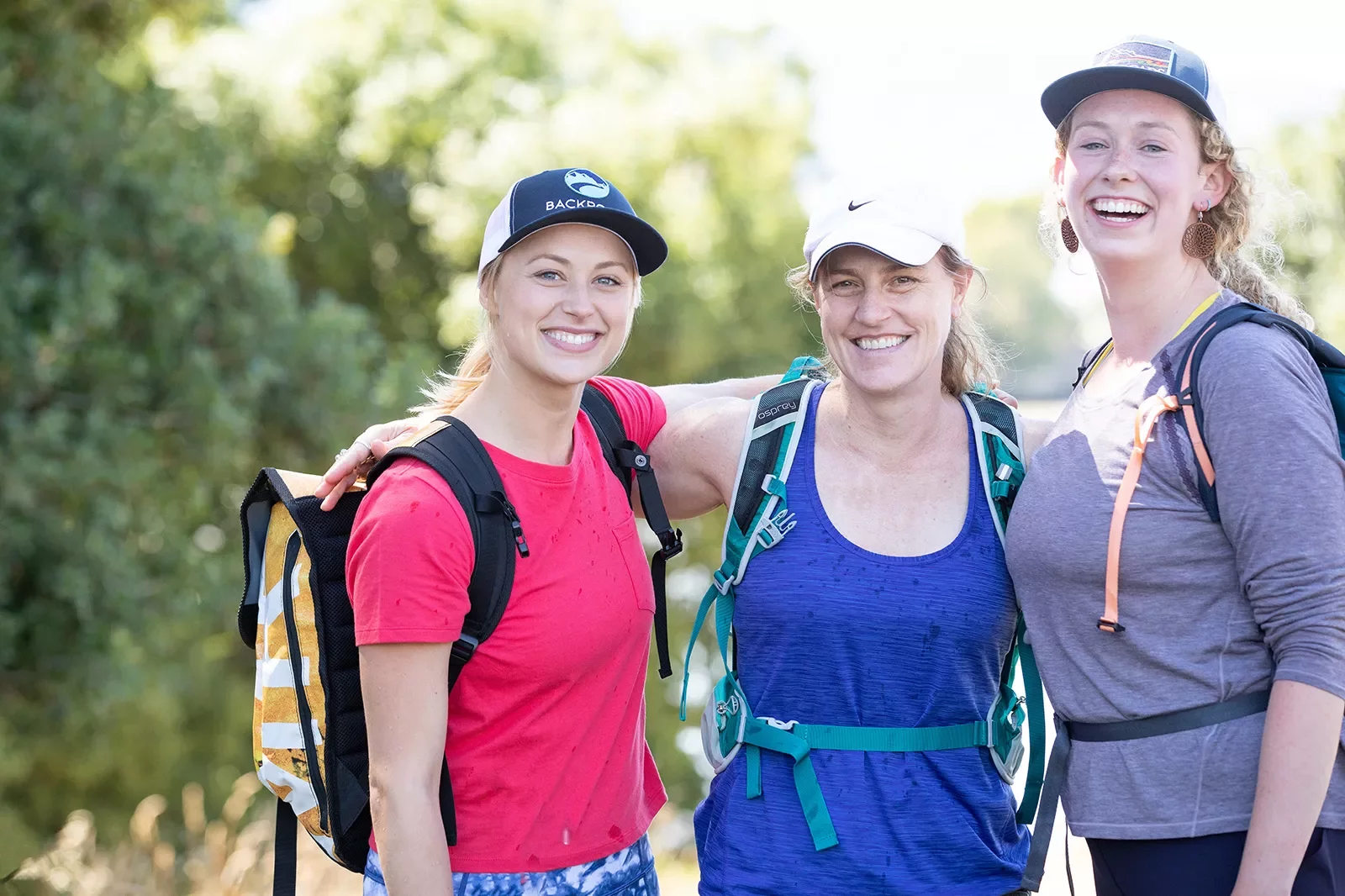 Three female hikers with arms around their shoulders