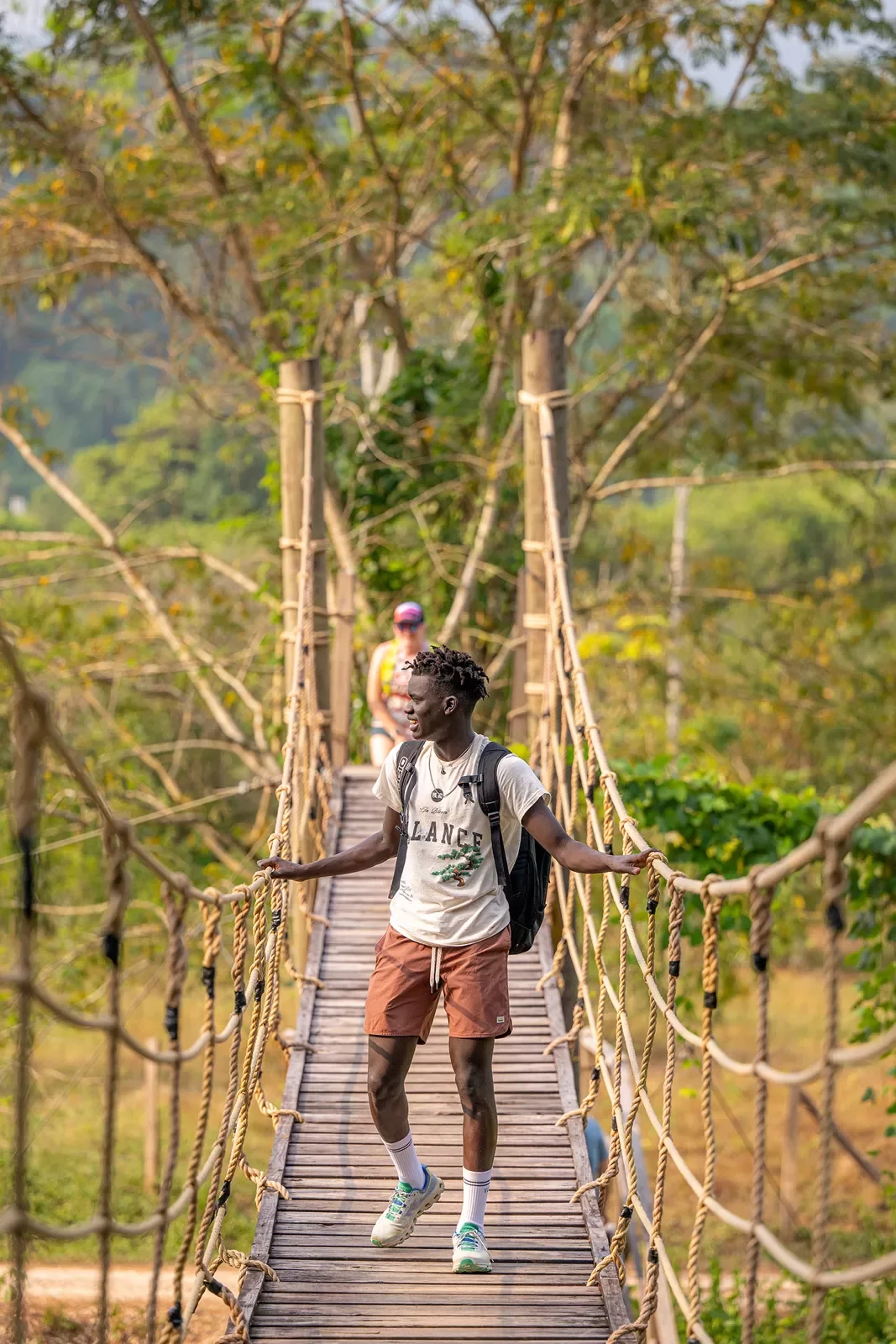Man walking across a rope and wooden bridge