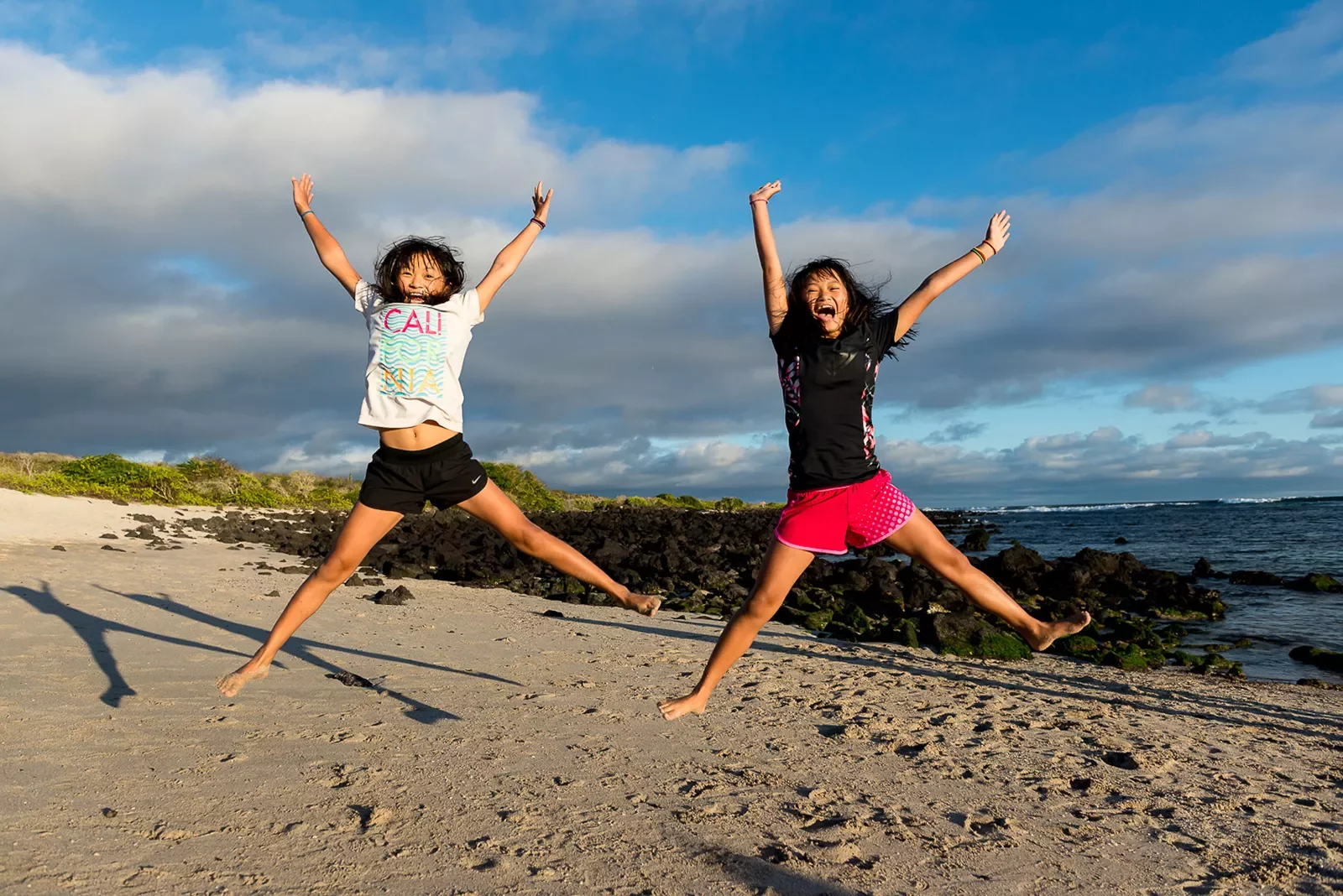 Two girls jumping on a beach