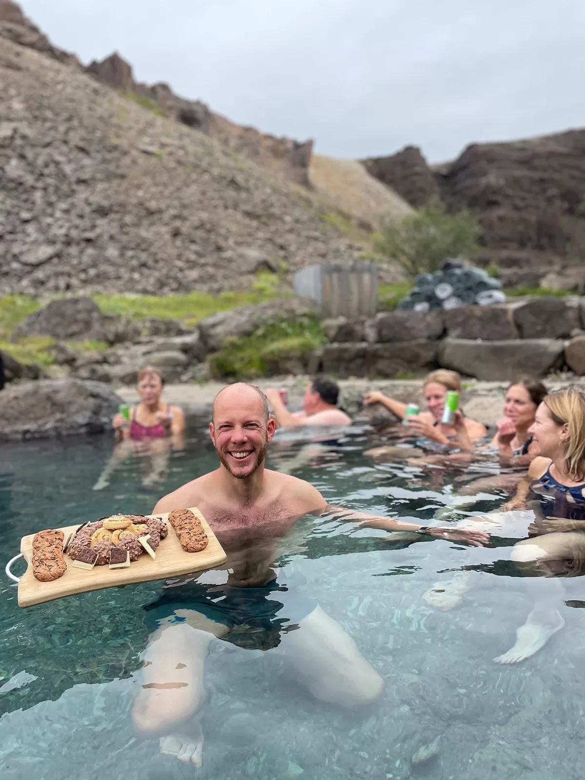 Man in a pool holding a cutting board full of cookies