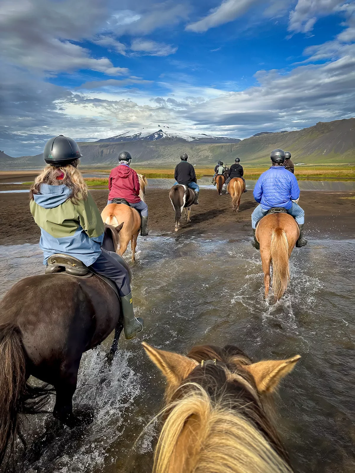 People riding horses in a shallow river