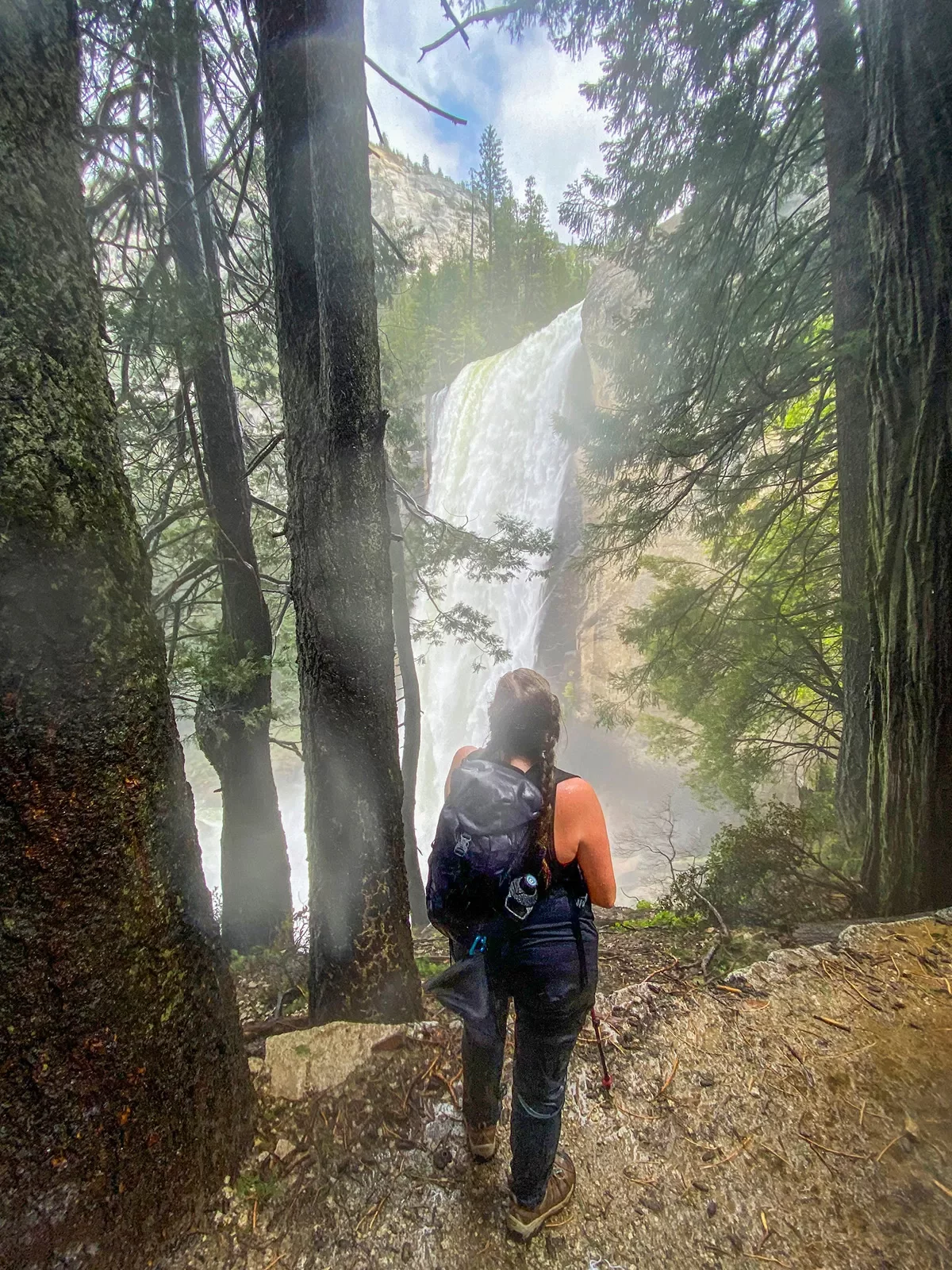 A hiker stops to admire a waterfall
