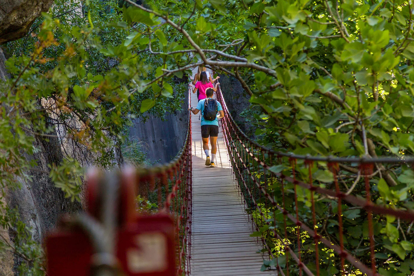 Group of people walking across a long, wooden bridge