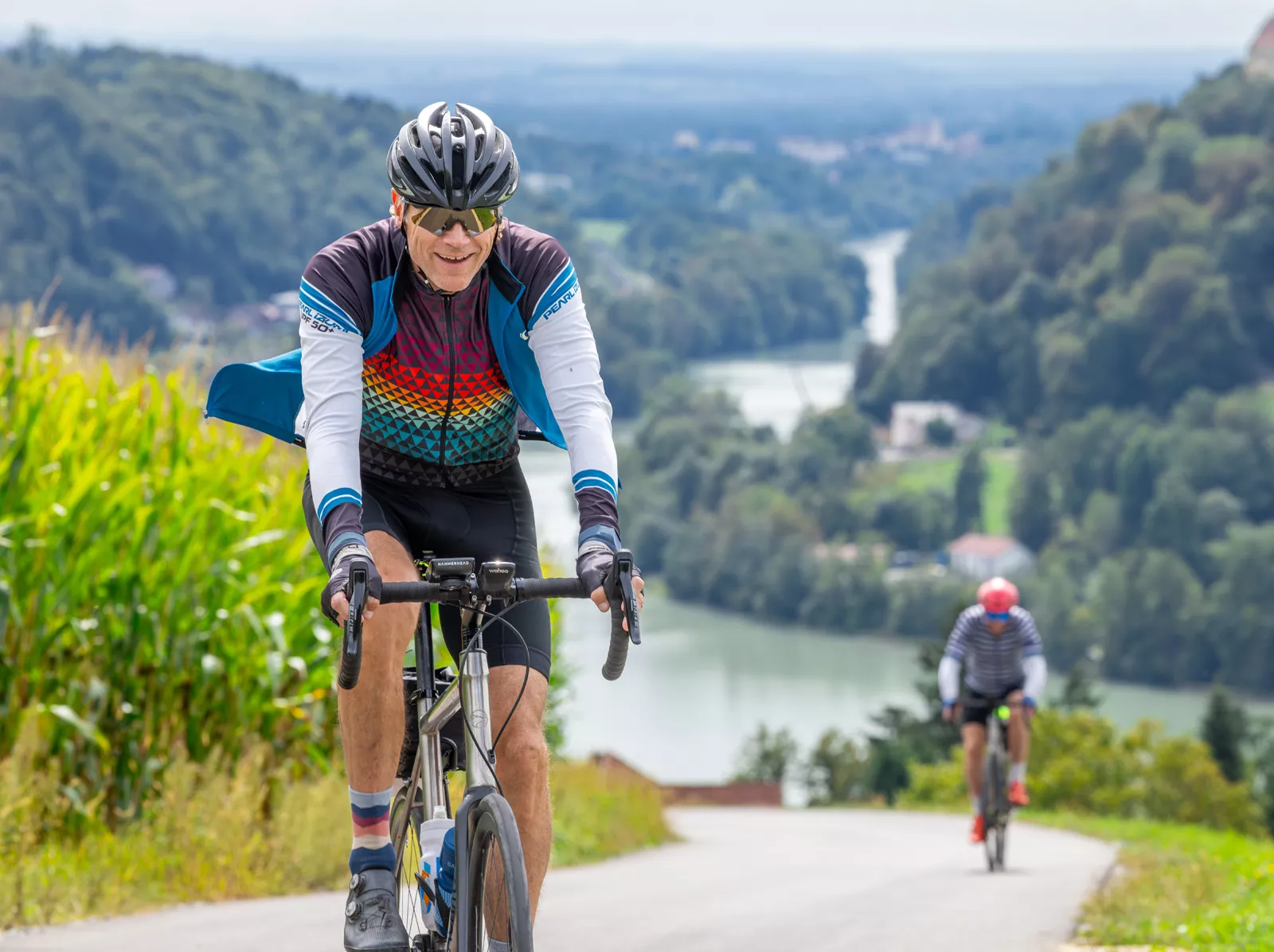 Man smiling while biking on a road, with a river in the distance