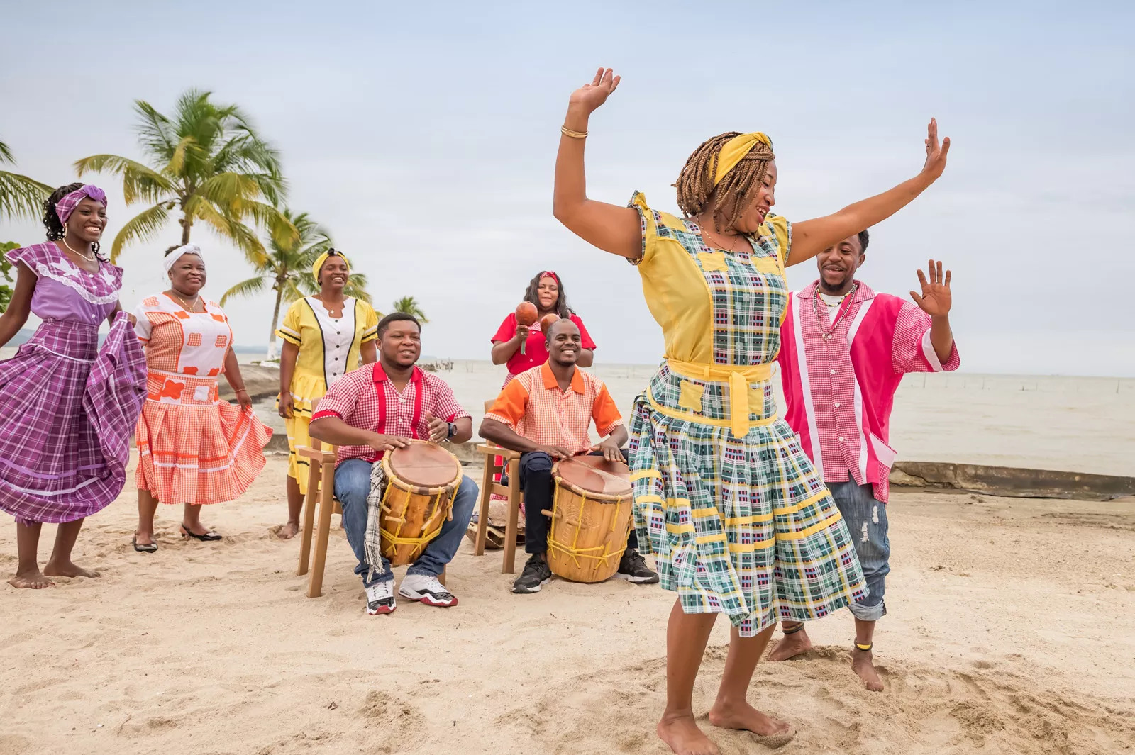 Two men playing large drums with a group of women dancing