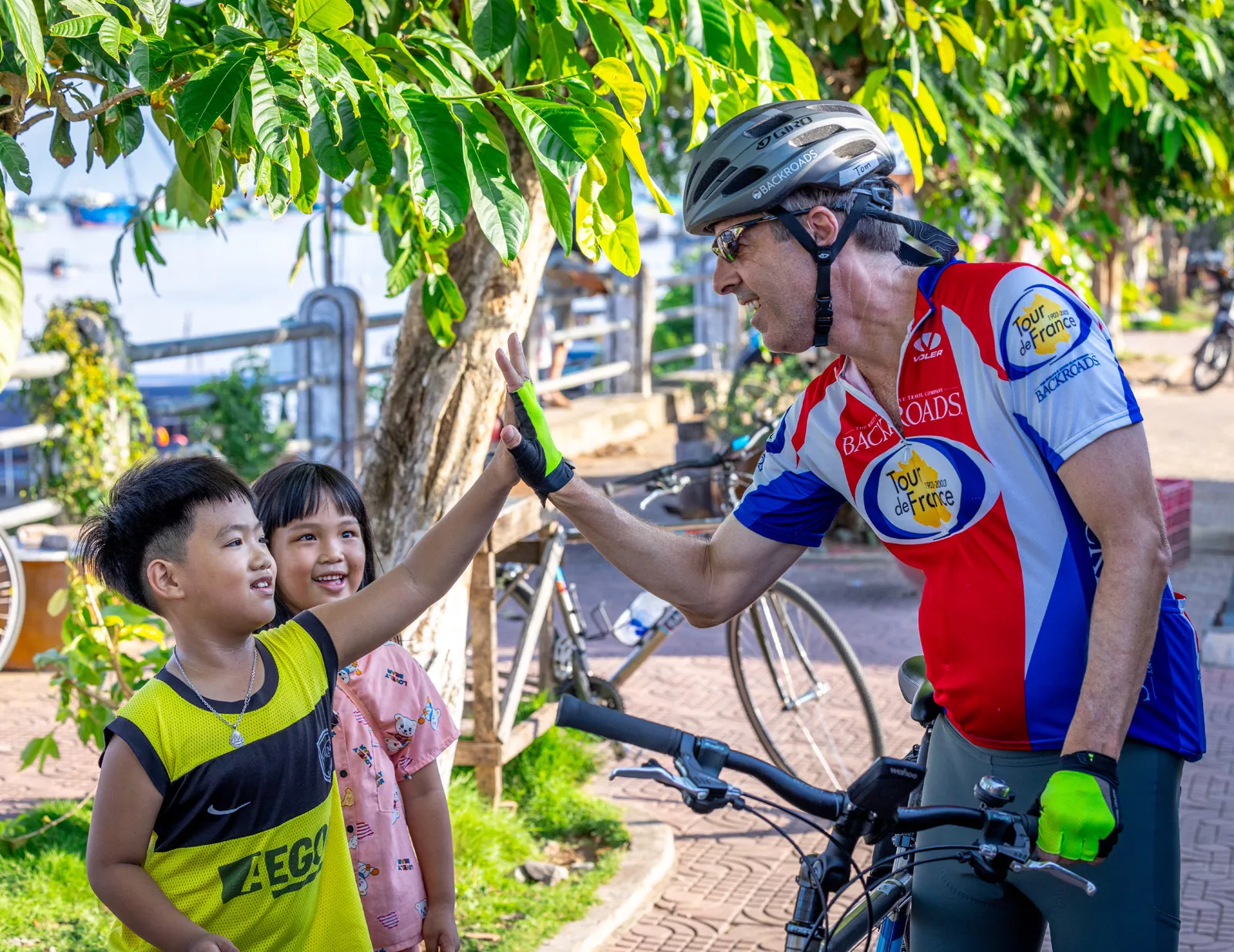 Man riding a bike while giving high fives to little kids
