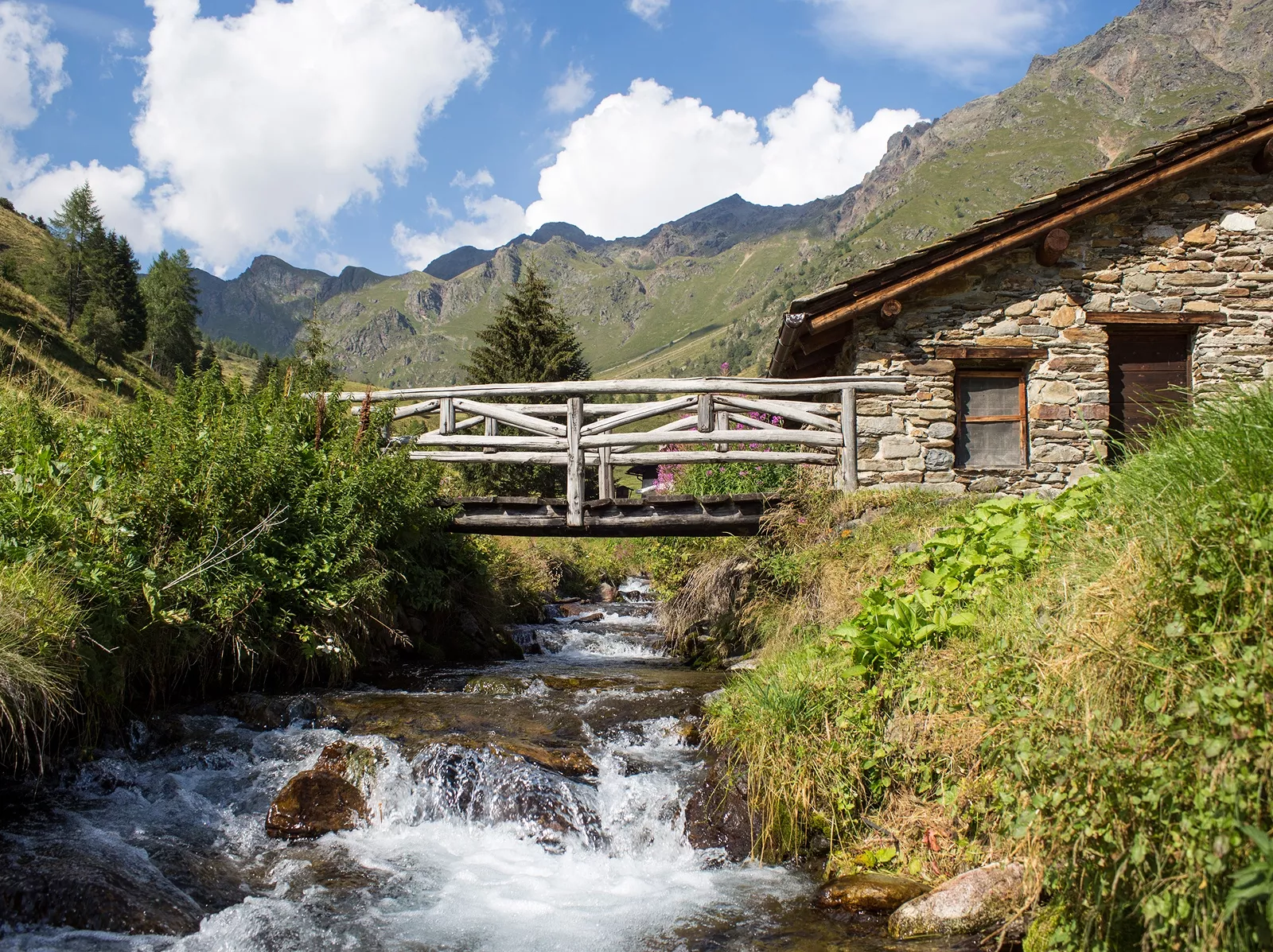 Small river under a wooden bridge attached to a stone building