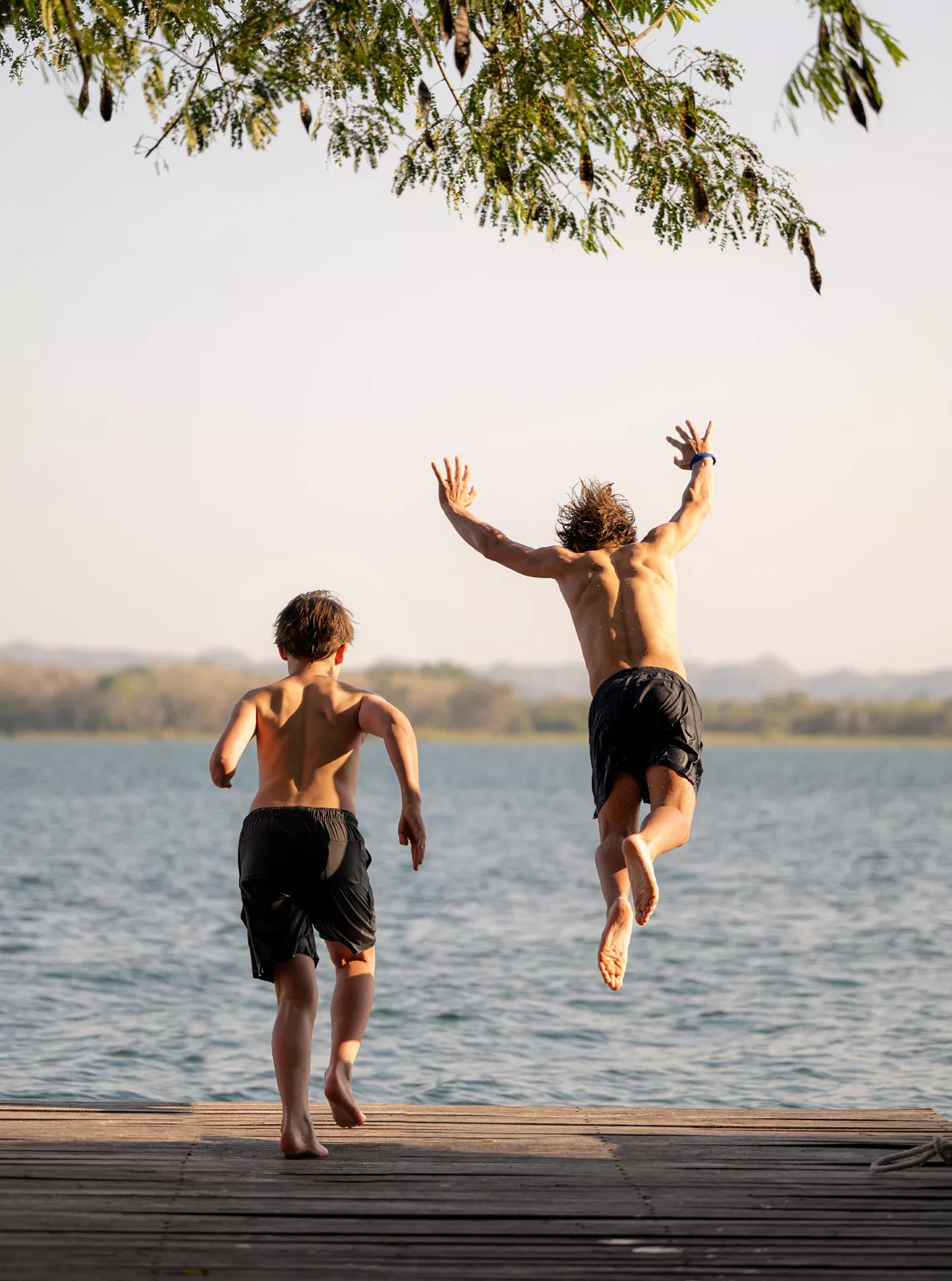 Two teenagers jumping into a large lake