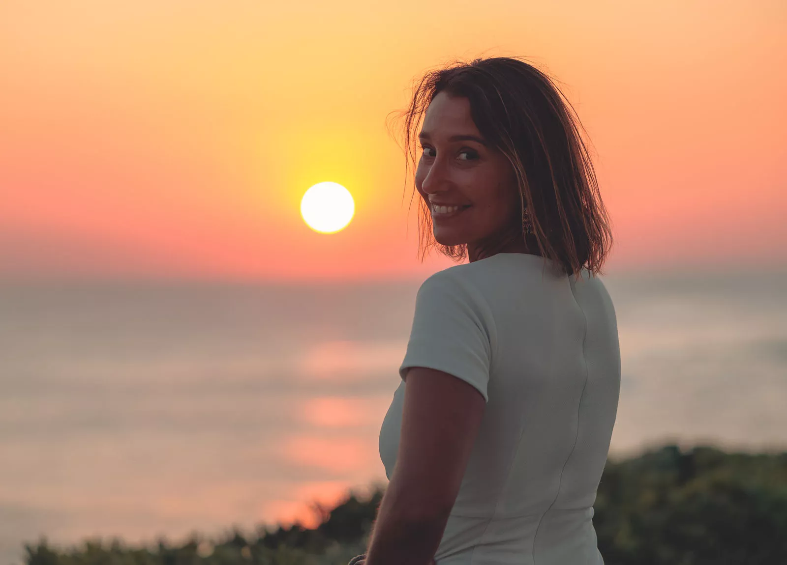 Woman looking back and smiling, with a sunset in the background