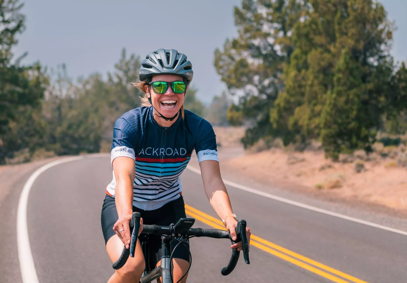 Woman smiling while riding a bike on an empty road